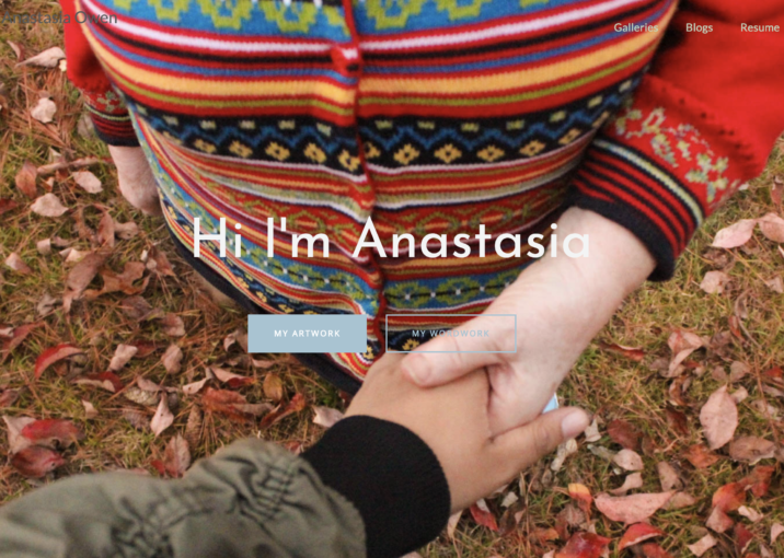 image: overhead cropped view of a perosn in a colorful striped sweater reaching out to ahand in a black cuffed grey coat. No faces are shown.